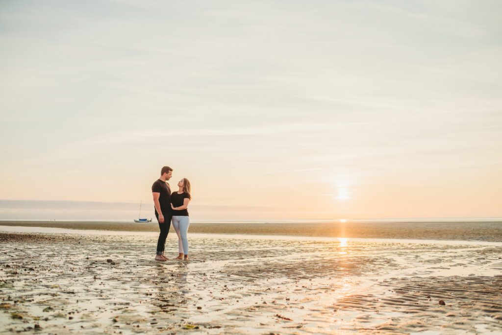 Engaged couple sharing a romantic moment during their beach engagement session at Crosby Landing Beach in Brewster, Massachusetts, on a beautiful July evening